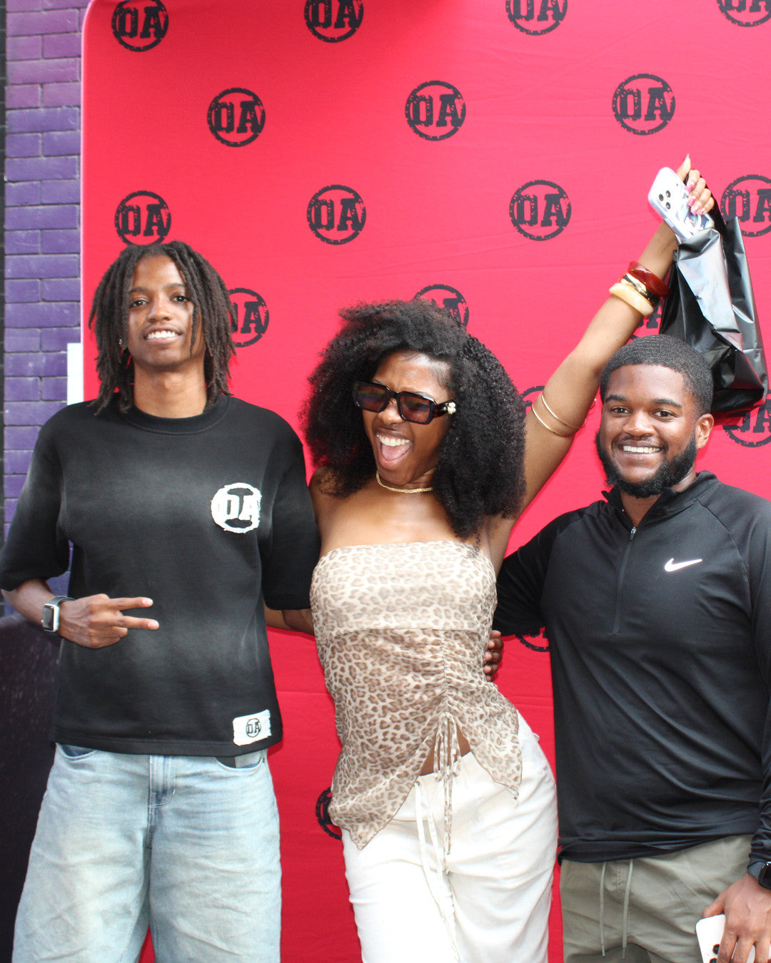 OA's founder and friends laughing at the OA backdrop, an OA bag in the air