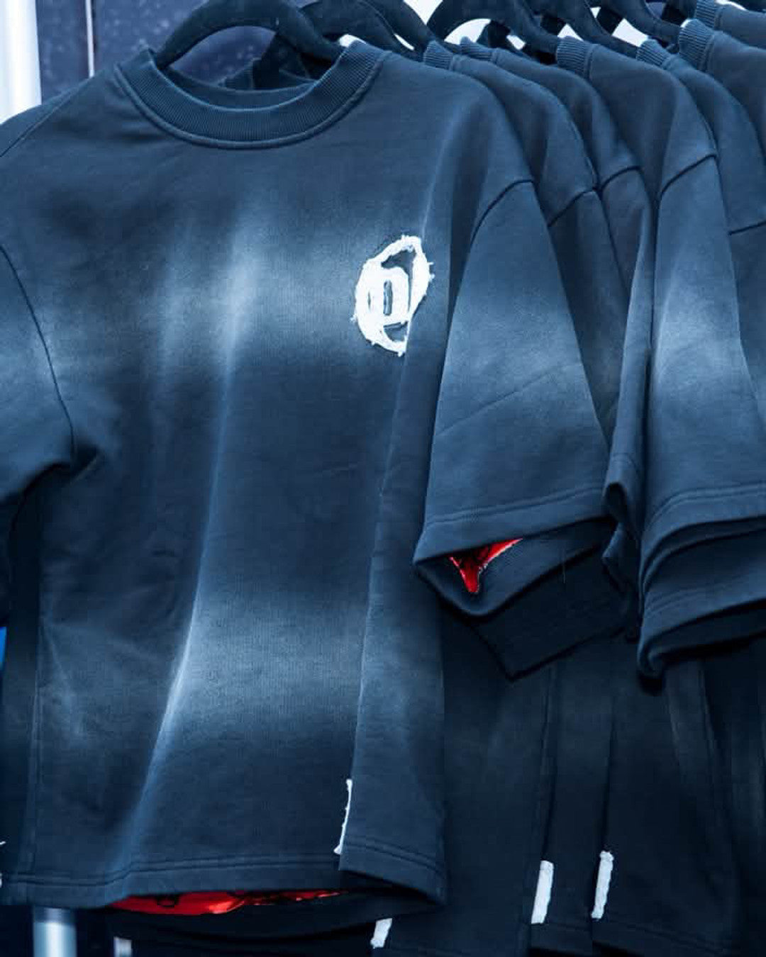Origin Blank tees on the rack with the red lining showing