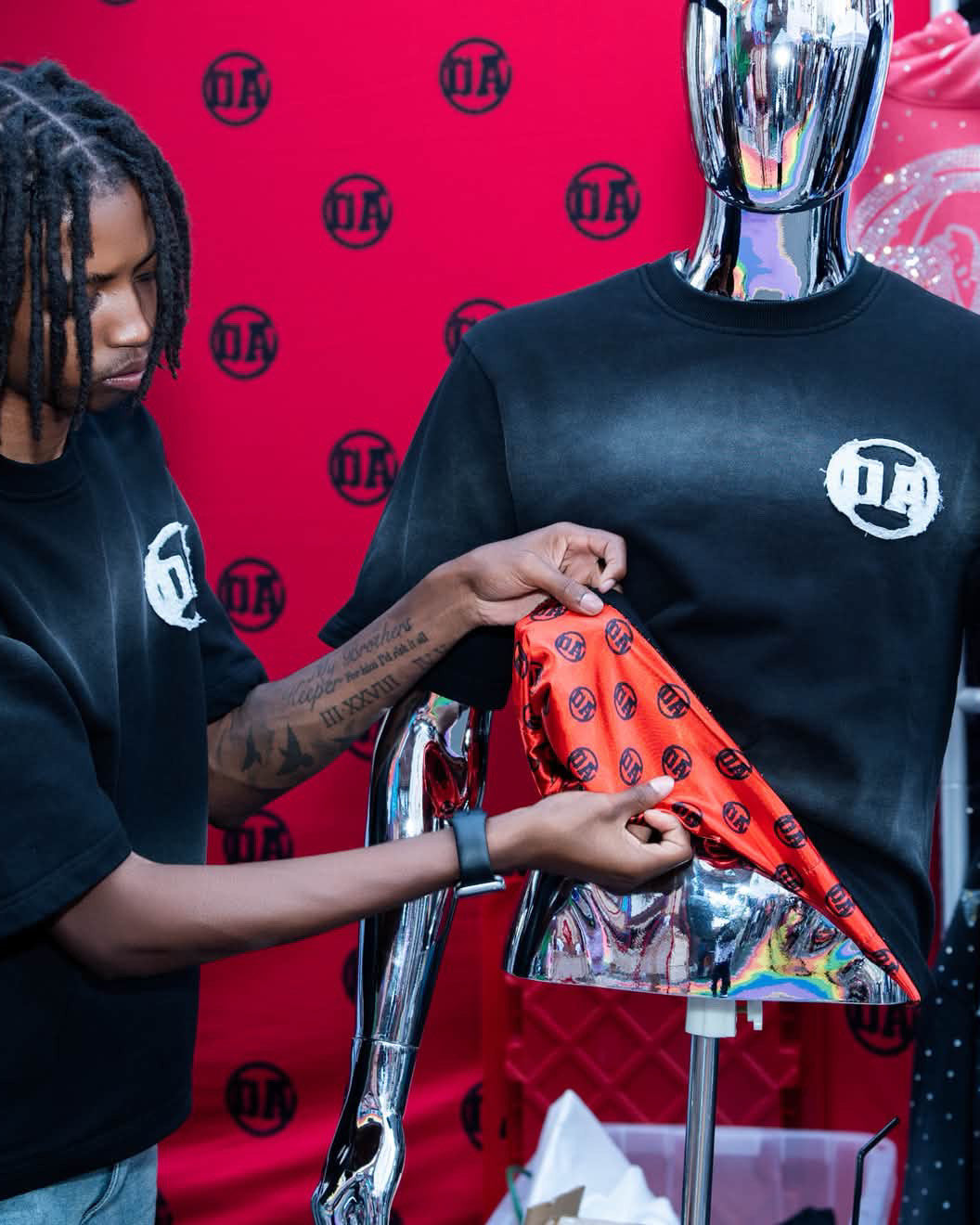 OA's founder pulling the red OA silk lining out of an Origin Blank tee at an OA pop-up