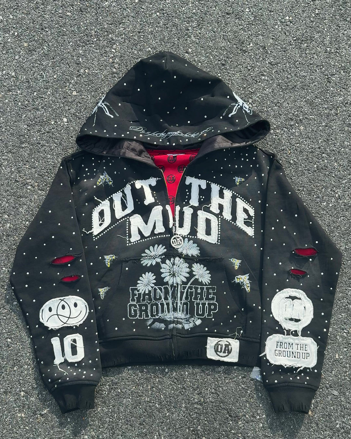 OUT THE MUD zip-up hoodie in black laid flat on the street, front