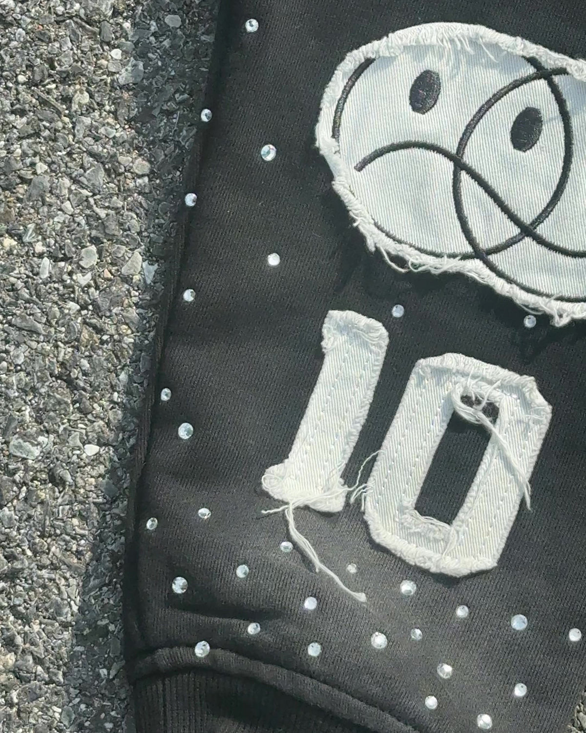 Close-up of the smiley and 10 patches on the OUT THE MUD sleeve
