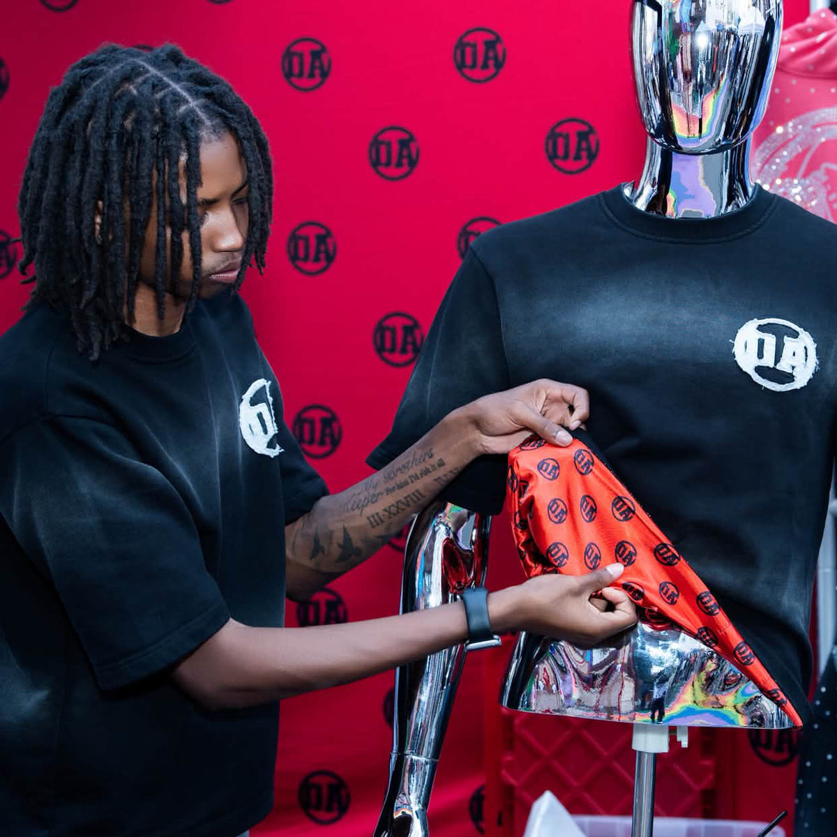 OA's founder pulling the red OA silk lining out of an Origin Blank tee at the July pop-up